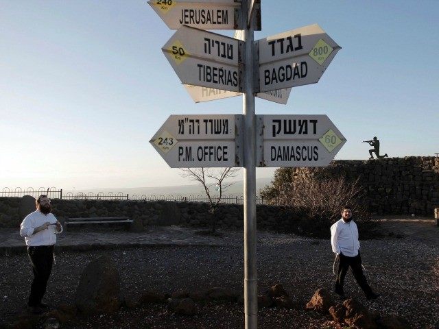 Israelis walk near a sign for tourists showing the distance to Damascus and Baghdad among other destinations at an army post on Mount Bental in the Israeli-annexed Golan Heights on March 10, 2016. Israel and Syria have formally been at war for decades though the demarcation line between them had …
