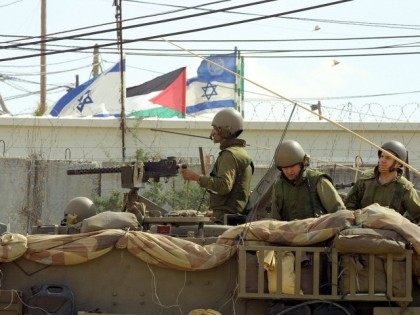 With a Palestinian flag to his back an Israeli soldier rides in an armored personnel carrier April 1, 2002 in the outskirts of the West Bank town of Qalqilia. I