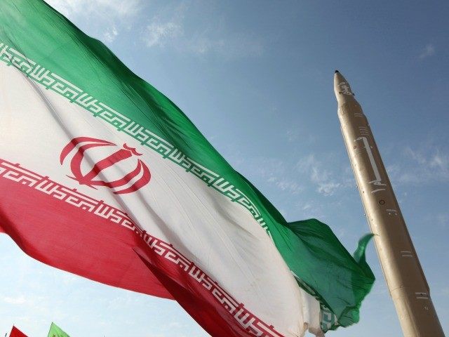 A picture taken on August 20, 2010 shows an Iranian flag fluttering at an undisclosed location in the Islamic republic next to a surface-to-surface Qiam-1 (Rising) missile which was test fired a day before Iran was due to launch its Russian-built first nuclear power plant.