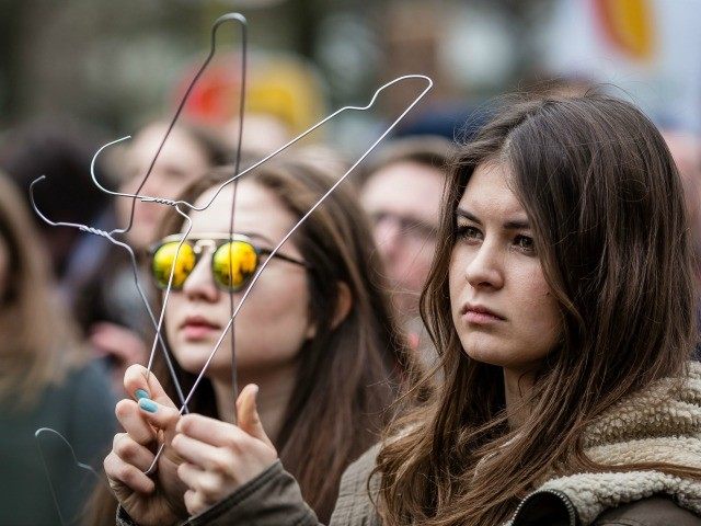 A woman holds coat hangers as a symbol of illegal abortion during an anti-government, pro-