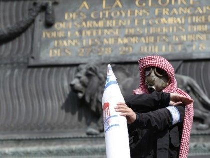 A protester wearing a gas mask and a kaffiyeh holds a fake rocket with the Israeli flag an