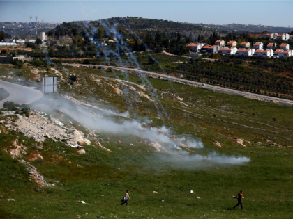 Palestinian protesters walk away amidst tear gas smoke during clashes with Israeli security forces following a march against Palestinian land confiscation on April 1, 2016 in the West Bank village of Nabi Saleh near Ramallah.