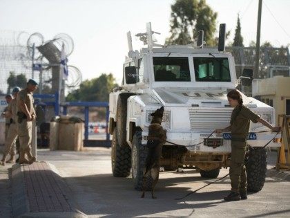 An Israeli soldier and her dog inspect a UN vehicle as Peacekeepers of the United Nations