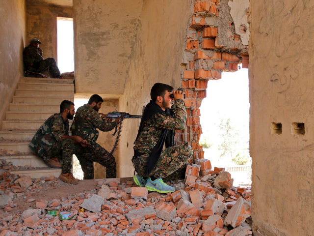 Kurdish People's Protection Units (YPG) fighters take up positions inside a damaged buildi