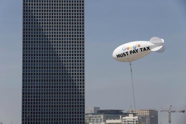 A blimp reading ''Google must pay tax'' is seen floating over the Tel
