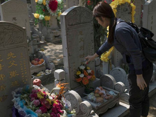 CHINA, BEIJING : TOPSHOT - A woman pours alcohol over a grave during the "Qingming" festival, or Tomb Sweeping Day, at a cemetary in Babaoshan in Beijing on April 4, 2016. During Qingming, Chinese traditionally tend the graves of their departed loved ones and often burn paper offerings to honour …