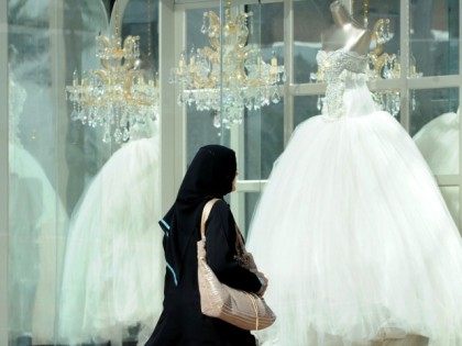 A Saudi woman walks past wedding dresses displayed in a shop window on February 4, 2013 at a mall in the Saudi capital Riyadh.