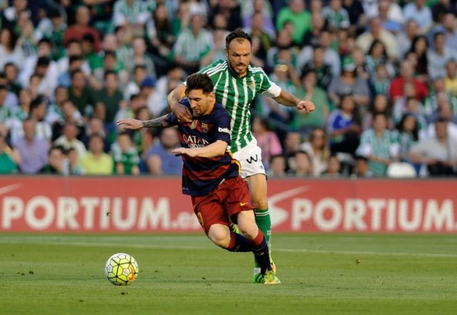 Barcelona's Lionel Messi fights off a challenge from Real Betis Balompie's Heiko Westerman