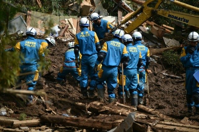 Police search for missing persons trapped under houses destroyed in a landslide in Minami-