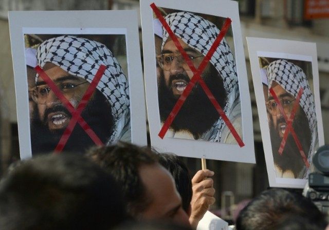 Activists carry placards of the chief of Jaish-e-Mohammad, Masood Azhar, during a protest