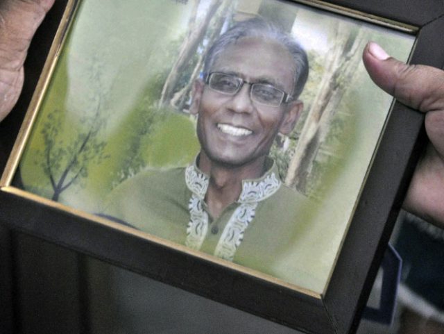 A man holds a portrait of Bangladeshi professor Rezaul Karim Siddique, who was hacked to d