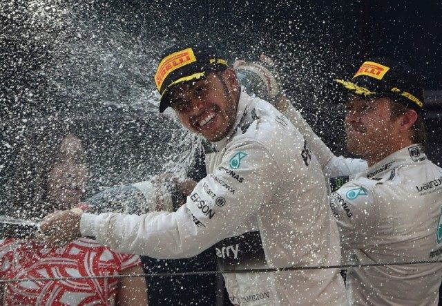 British F1 driver Lewis Hamilton (C) is sprayed with champagne by teammate Nico Rosberg (R