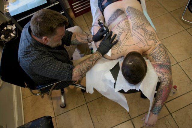 Butch Johnson, owner of Champion Tattoo Company, works on a former US Marine at his art st