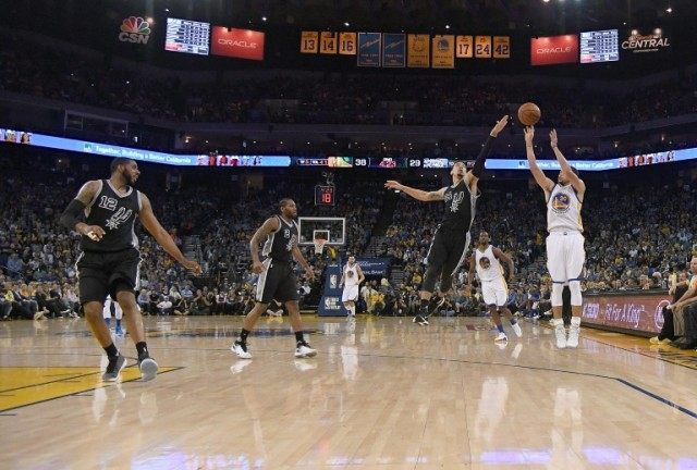 Stephen Curry (R) of the Golden State Warriors shoots and makes a three-point basket over