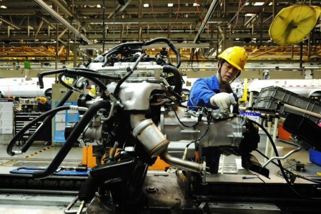 An employee works on an engine at the assembly line of a car factory in Qingdao, eastern C
