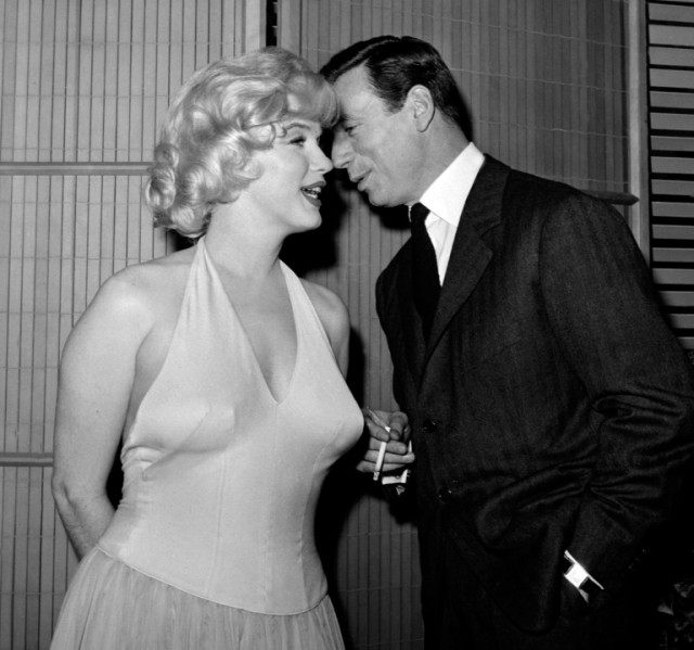 US actress Marilyn Monroe, listens as her co-star, French actor and singer Yves Montand wh
