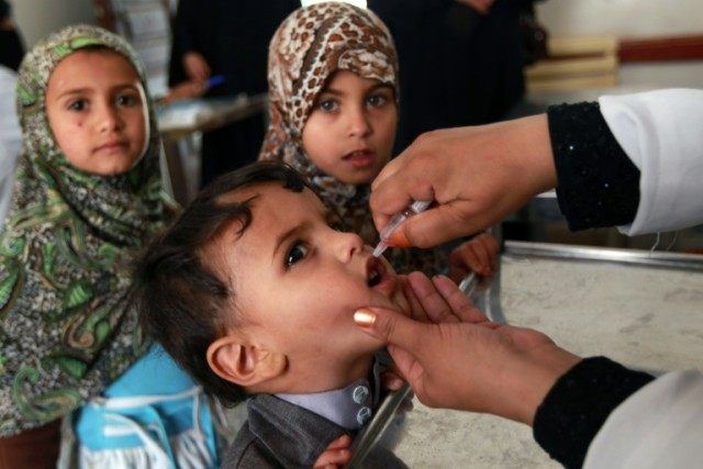 A health worker gives a young boy drops of oral polio vaccine on April 7, 2014 in an outsk