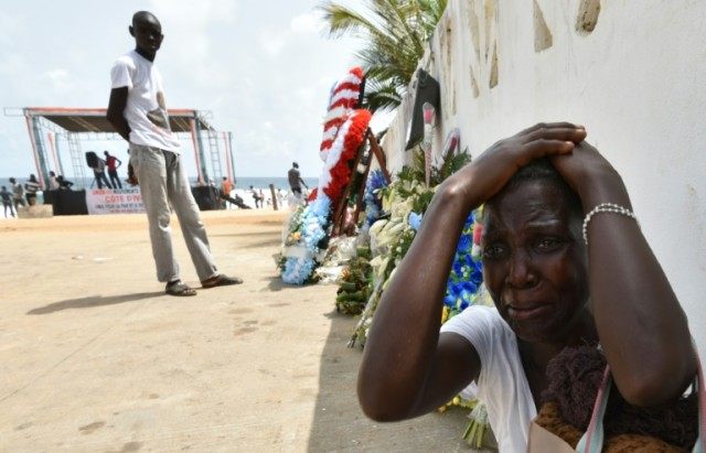 A woman cries next to wreaths of flowers in front of the Etoile du Sud hotel on March 20,
