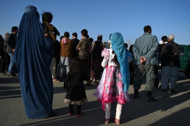 An Afghan woman and children near the gate of Ministry of Defence in Kabul on February 27,