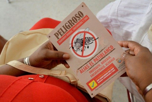 A woman holds a leaflet with information on the Aedes aegypti mosquito, which carries Zika