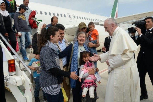 Pope Francis welcomes a group of Syrian refugees after landing at Ciampino airport in Rome