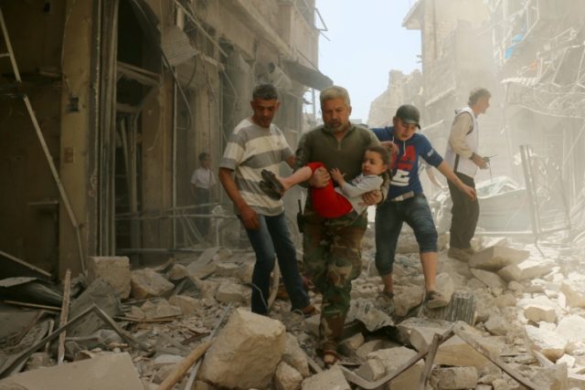 A Syrian man carries a child as they evacuate an area following a reported airstrike on Ap