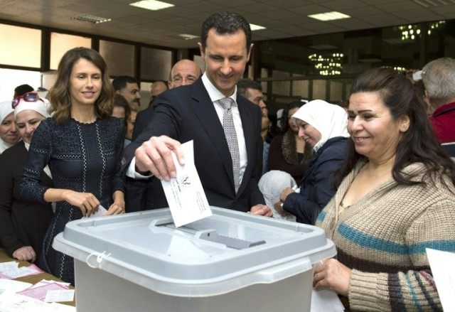 Syrian President Bashar al-Assad (C) and his wife Asma (L) cast their votes at a polling s