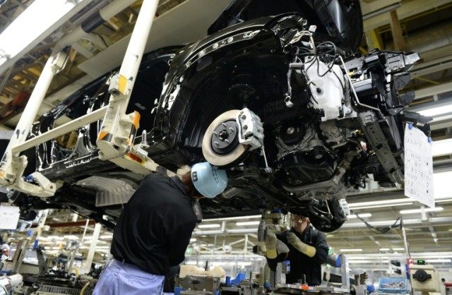 Employees of Toyota Motor Kyushu mount an engine into the body of a Lexus on an assembly l