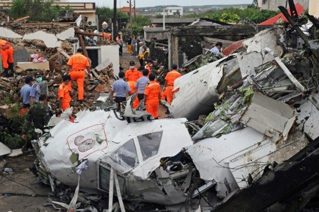 Rescue workers and firefighters search through the wreckage of TransAsia Airways flight GE