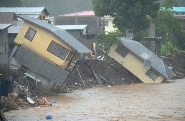Flood waters run past damaged homes in the Solomon Islands' capital Honiara on April 4, 20