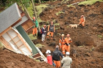 Rescuers and their guide dogs search for victims buried in a landslide due to the recent earthquakes in the village of Minami-Aso, Japan's Kumamoto prefecture, on April 18, 2016