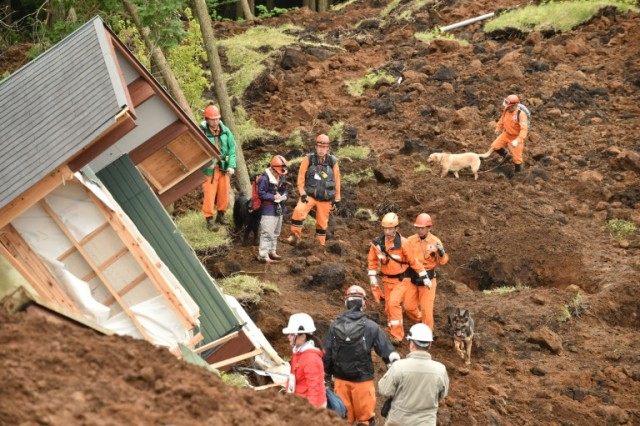Rescuers and their guide dogs search for victims buried in a landslide due to the recent e