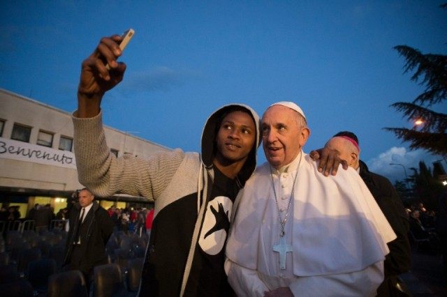 Pope Francis poses for a selfie with a migrant during his visit to the Castelnuovo di Port