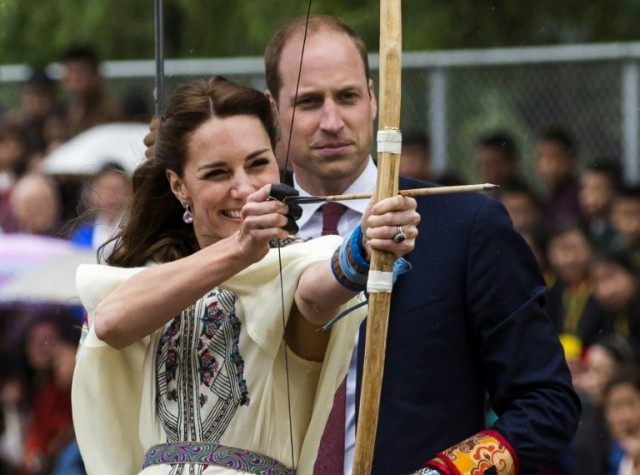 Kate, the Duchess of Cambridge, fires an arrow as Prince William looks on at the Changling