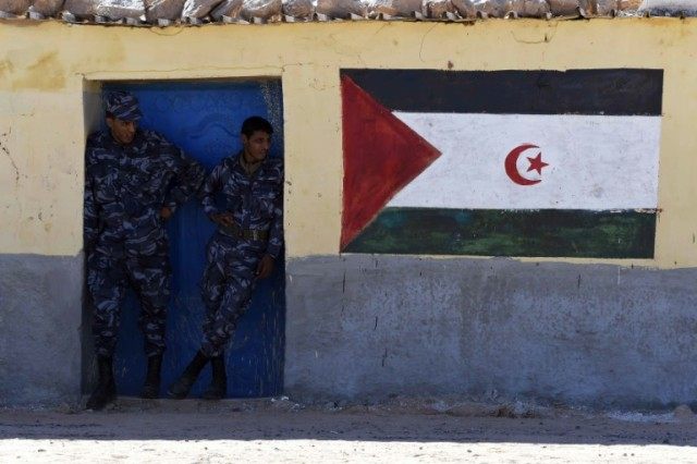 Security men stand next to a mural with the Western Sahara flag at the Smara refugee camp