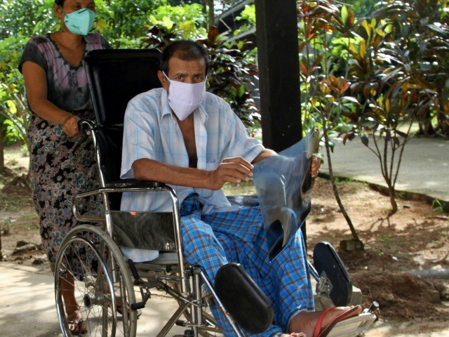 Carrying his X-ray result, a patient rides on a wheel chair at National Tuberculosis Reference Laboratory Tuesday, Sept 10, 2013, in outskirts of Yangon, Myanmar. UNITAID delivered nearly 23,000 TB test cartridges and four GeneXpert machines for quick diagnosis of TB and drug-resistant TB in Myanmar. Tuberculosis is an age-old scourge and one of the world's most infectious killers affecting 12 million people, according to WHO. With 506 sufferers per 100,000 people, Myanmar's rate of regular TB is three times the global average. (AP Photo/Khin Maung Win)