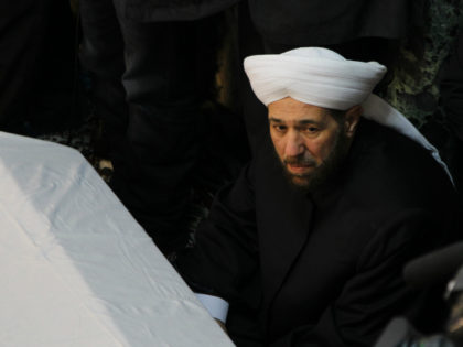 Syria's Grand Mufti Ahmed Badr al-Din al-Hassoun sits near the coffins of a senior pro-Syr