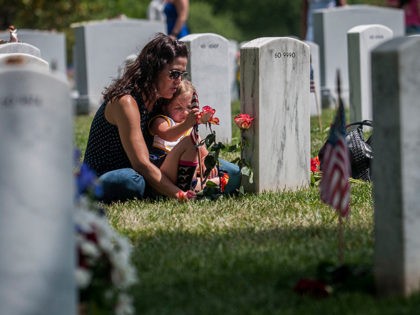 Angela Spraul and her daughter Ava, 4, sit at the grave of her husband John Spraul, U.S. N