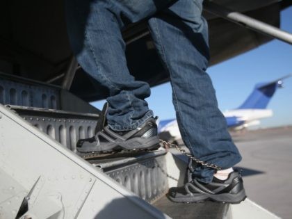 A Honduran immigration detainee, his feet shackled and shoes laceless as a security precaution, boards a deportation flight to San Pedro Sula, Honduras on February 28, 2013 in Mesa, Arizona.
