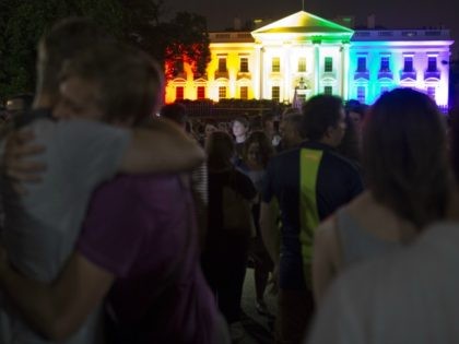 A gay couple hugs in front of the White House lightened in the rainbow colors in Washingto