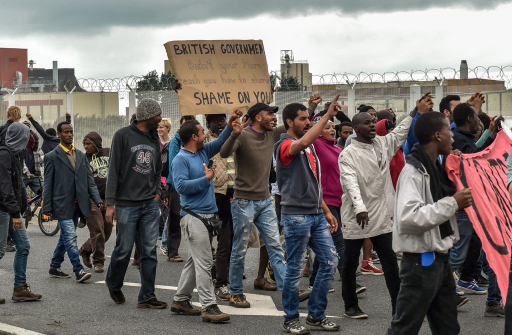 Illegal migrants demonstrate against British government, on August 20, 2015 in Calais, on the occasion of the visit of Britain's Home Secretary visit to Calais to sign a deal aimed at alleviating the migrant crisis. As part of the deal, the Home Office said Thursday that British police officers will be deployed to Calais to combat gangs smuggling the migrants across the Channel. AFP PHOTO/PHILIPPE HUGUEN (Photo credit should read PHILIPPE HUGUEN/AFP/Getty Images)