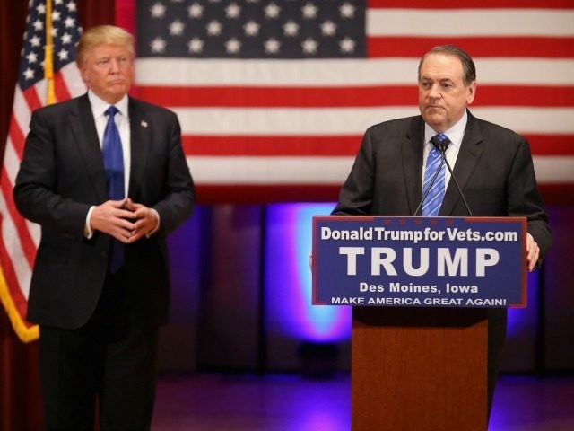 Republican presidential candidate Donald Trump (L) listens as fellow candidate Mike Huckab