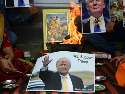 An Indian Hindu priest performs a Hawan (The Sarced Fire)ritual alongside posters bearing