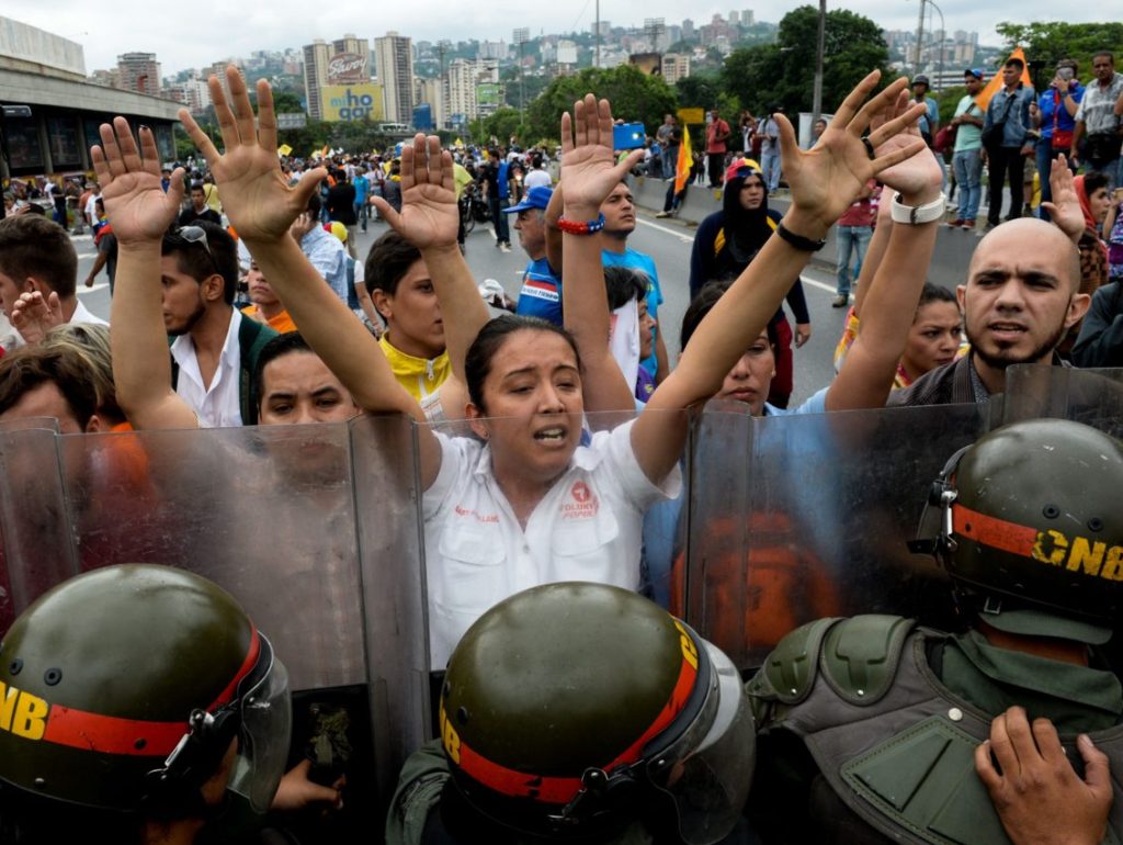 Opponents to the government of Venezuelan President Nicolas Maduro demonstrate in front of a line of riot police in Caracas on May 11, 2016. Riot cops fired tear gas to head off a protest march Wednesday by opponents of Venezuela's President Nicolas Maduro who were demanding a referendum on removing him from office. / AFP / FEDERICO PARRA (Photo credit should read FEDERICO PARRA/AFP/Getty Images)