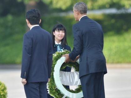 President Barack Obama (R) receives flowers to give as Japanese Prime Minister Shinzo Abe