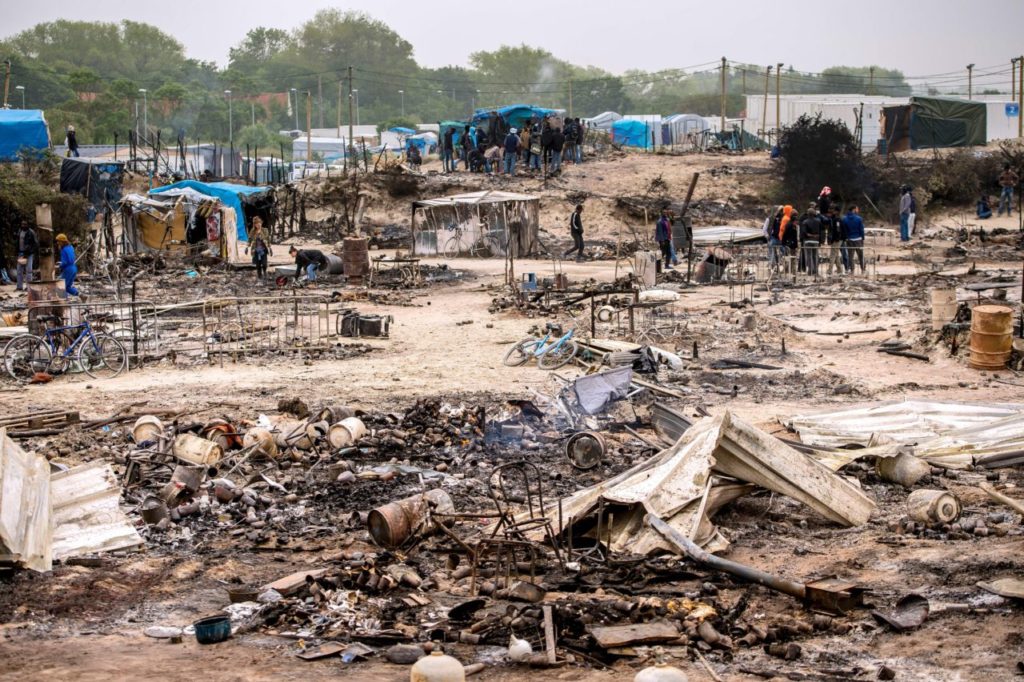 Migrants look at the burnt tents after a massive brawl that left 40 people injured in the "Jungle" migrant camp in the northern French town of Calais on May 27, 2016. Some 20 people living in the "Jungle" refugee camp in the northern French port of Calais were injured in a brawl between around 200 Afghans and Sudanese on May 26, 2016. / AFP / PHILIPPE HUGUEN (Photo credit should read PHILIPPE HUGUEN/AFP/Getty Images)