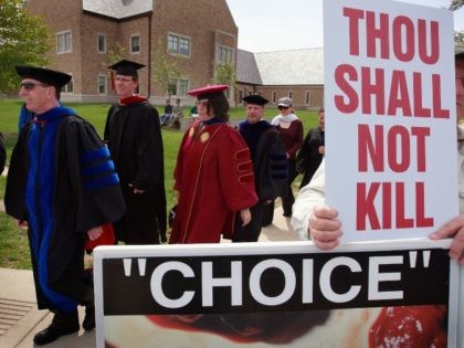 Participants in the Notre Dame Graduation ceremony pass anti-abortion activists on the way