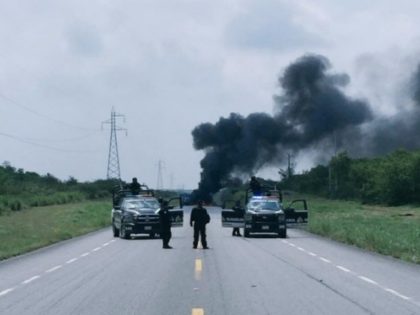 Mexican police keep a perimeter after cartel gunmen set fire to a truck in an effort to cl