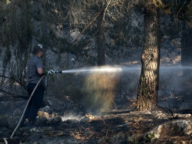 A firefighter douses a fire on July 25, 2010, in the Jerusalem forest. Thousands of homes