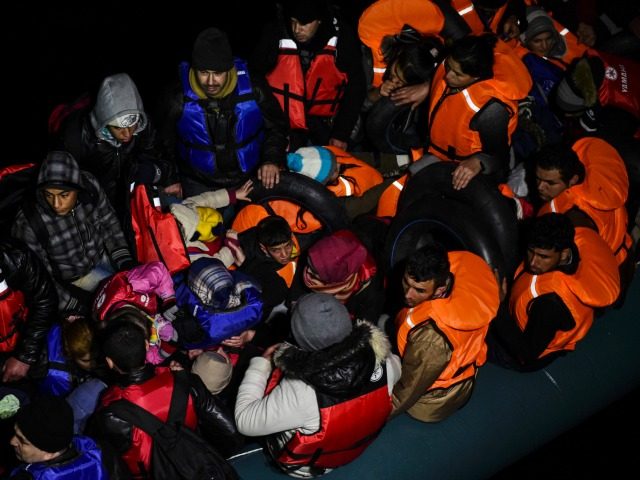 Syrian migrants wait aboard an inflatable dinghy after being rescued while attempting to r